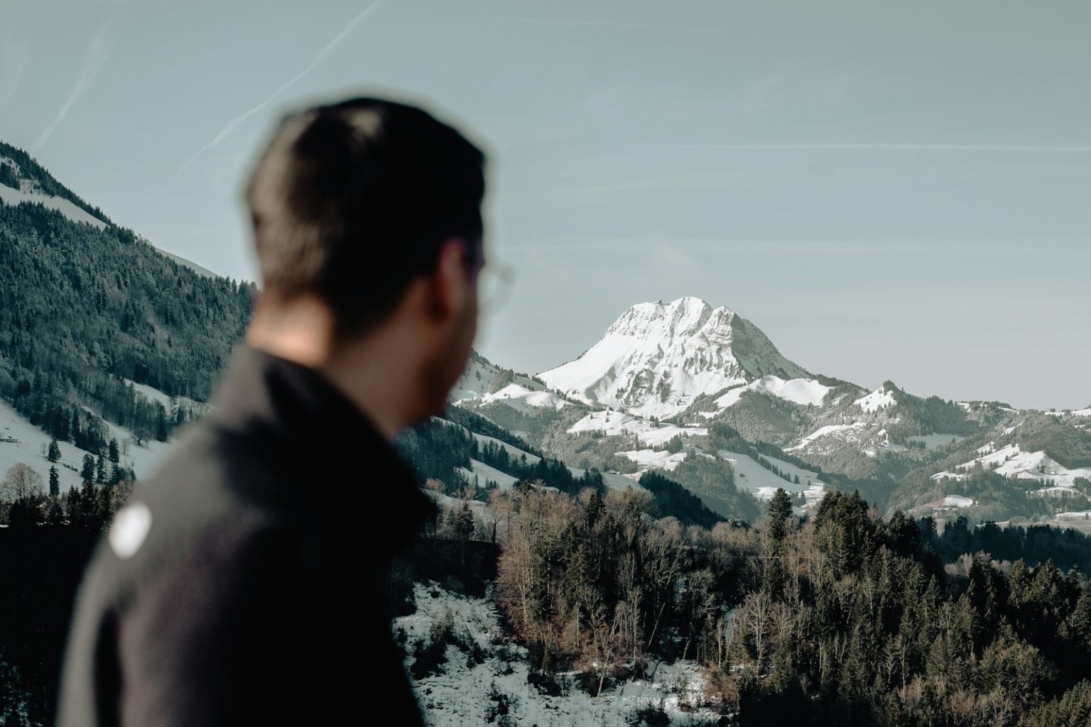 a man standing in front of a snow covered mountain